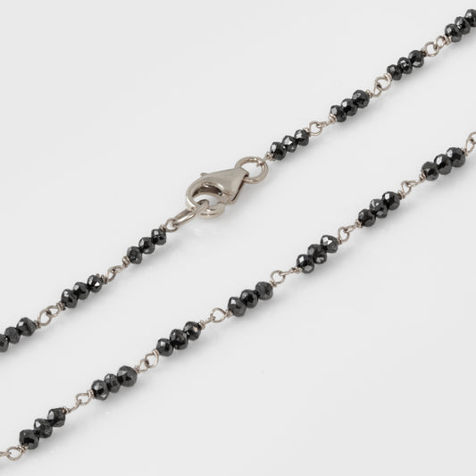 Bracelet with black beads and white gold clasp on a white background