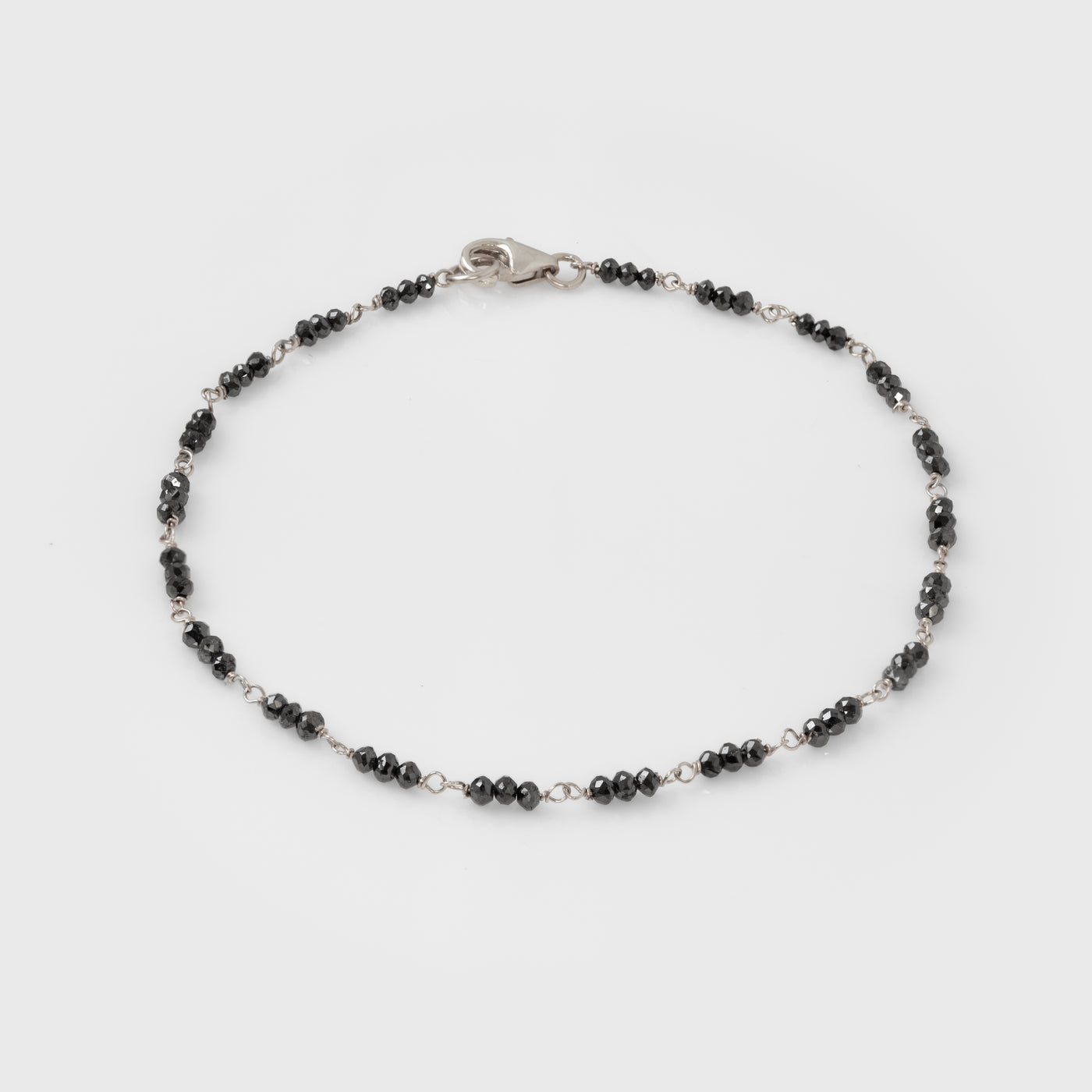 Bracelet with black beads and white gold clasp on a white background