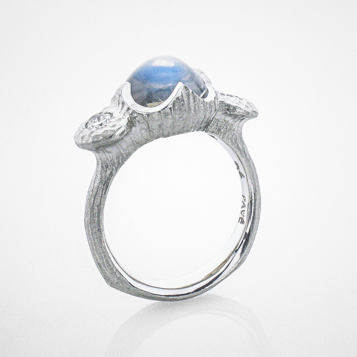 A platinum ring with a moonstone centerstone and diamond accents.