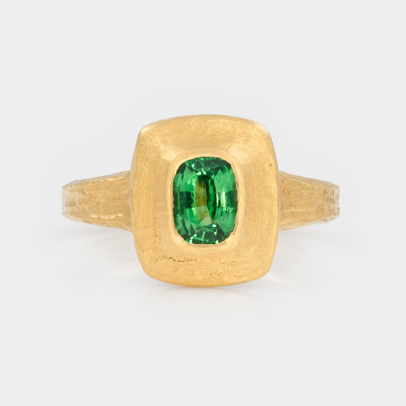Gold ring with a green garnet gemstone on a white background