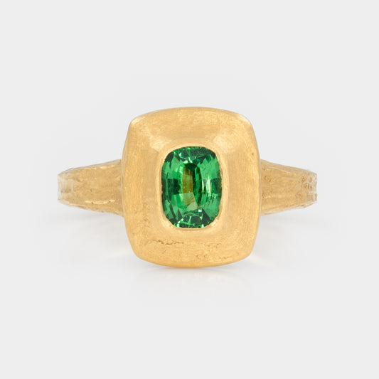 Gold ring with a green garnet gemstone on a white background