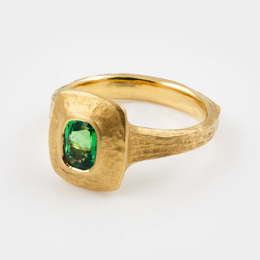 Gold ring with a green gemstone on a white background, three fourths angle