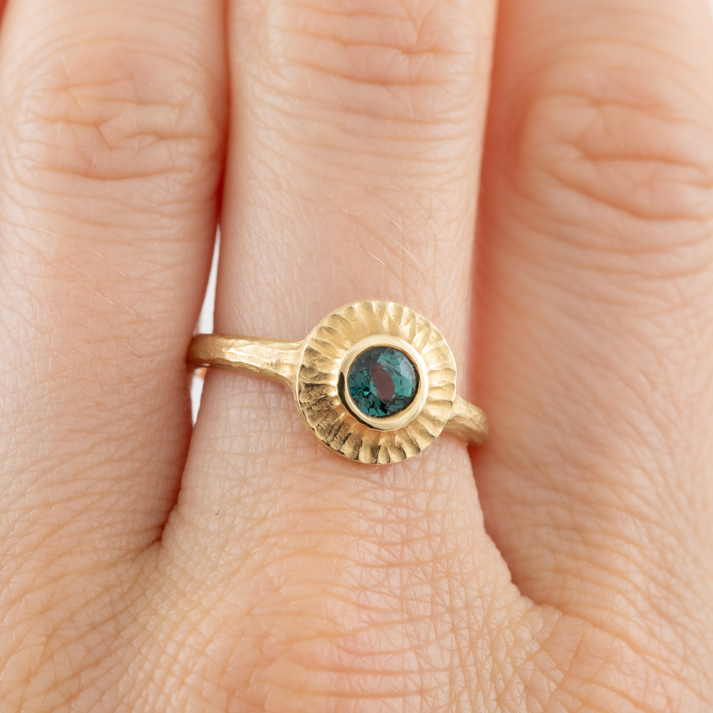 Gold ring with a green gemstone on a finger