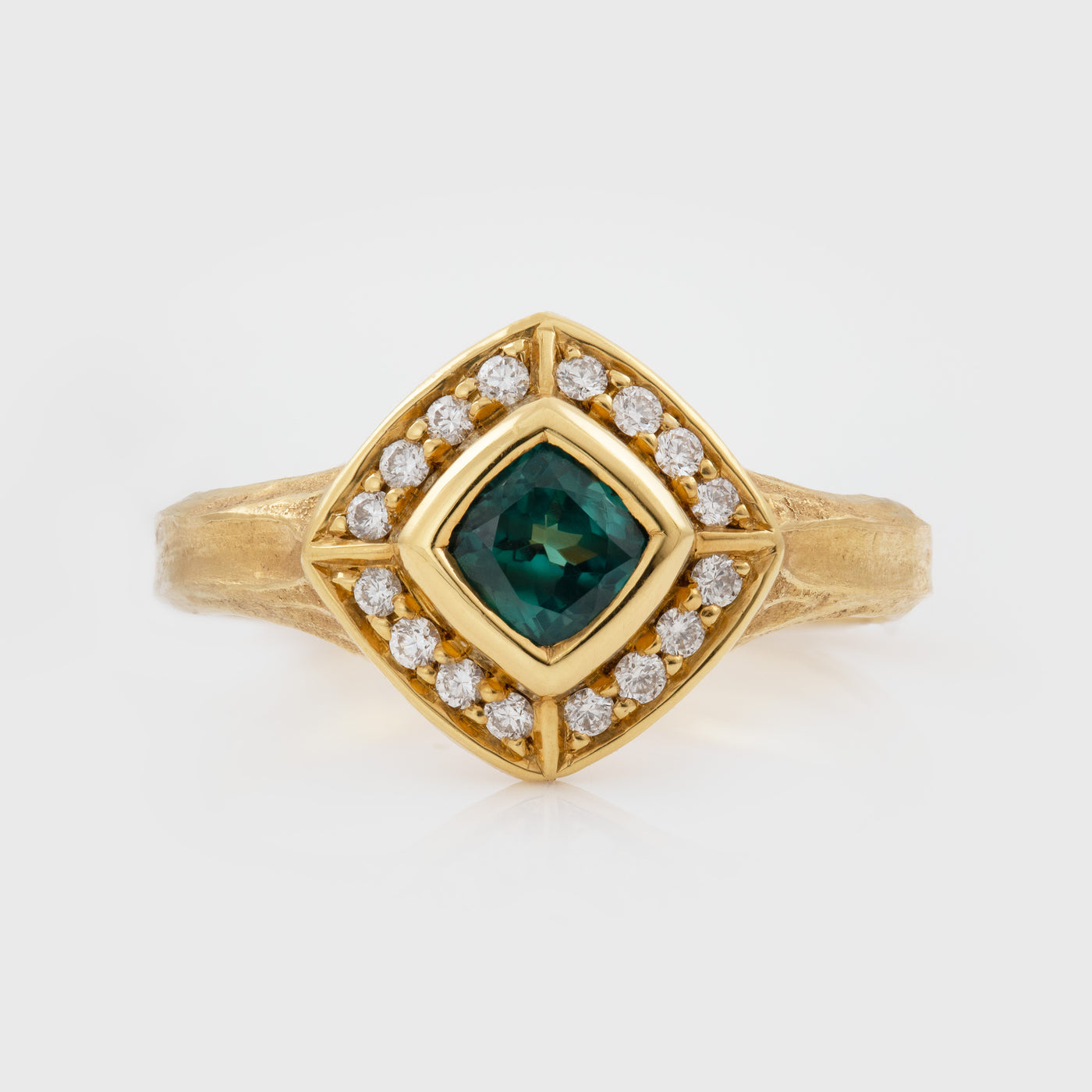 Gold ring with a green Alexandrite gemstone and diamond accents on a white background