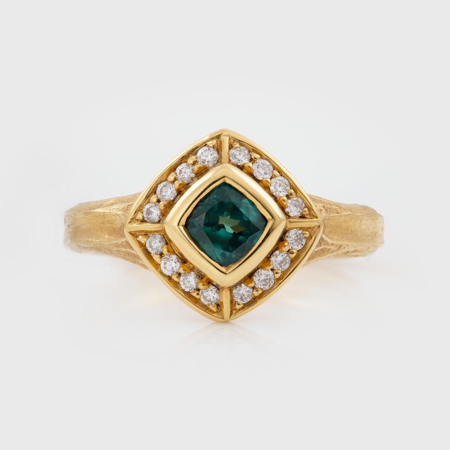 Gold ring with a green Alexandrite gemstone and diamond accents on a white background