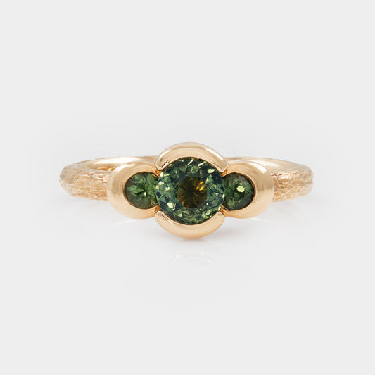 Gold ring with green sapphire gemstones on a white background