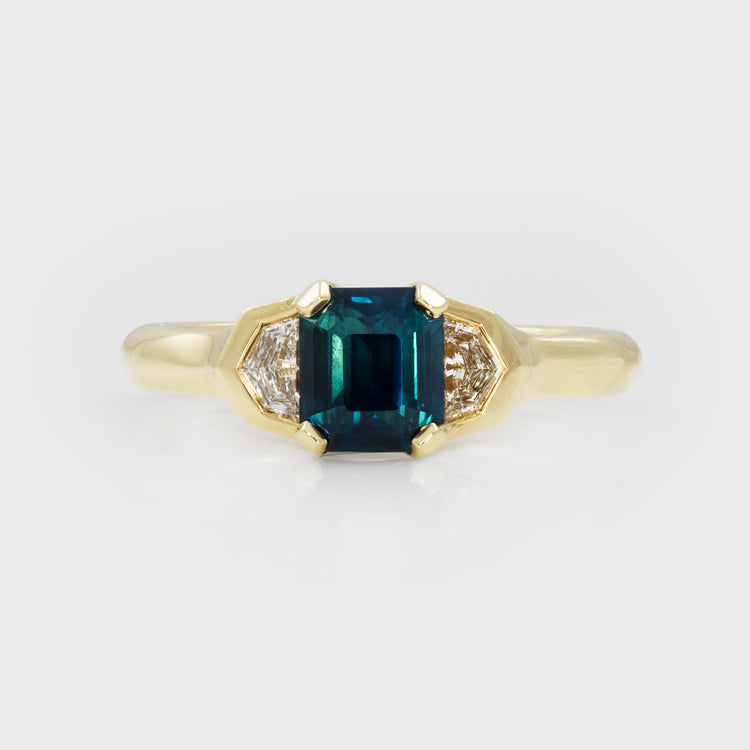 Gold ring with a bicolor blue-green gemstone and smaller diamonds on a light gray background