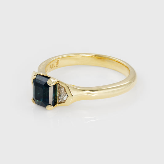 Gold ring with a bicolor blue-green gemstone and smaller diamonds on a light gray background
