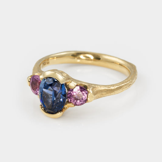 Gold ring with blue and pink gemstones on a white background