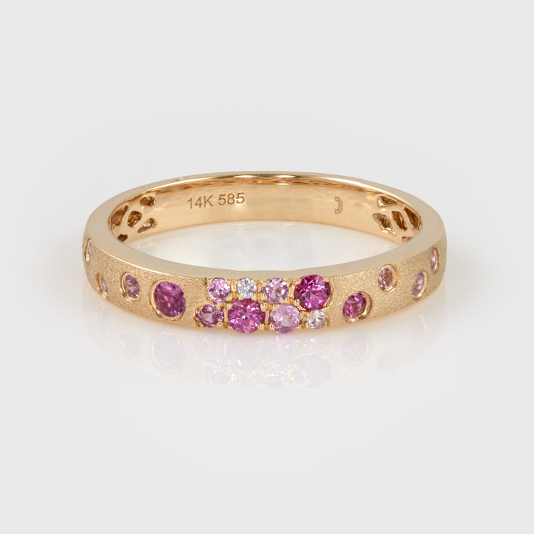 Close-up of a 14k yellow gold band with pink sapphires and rubies.
