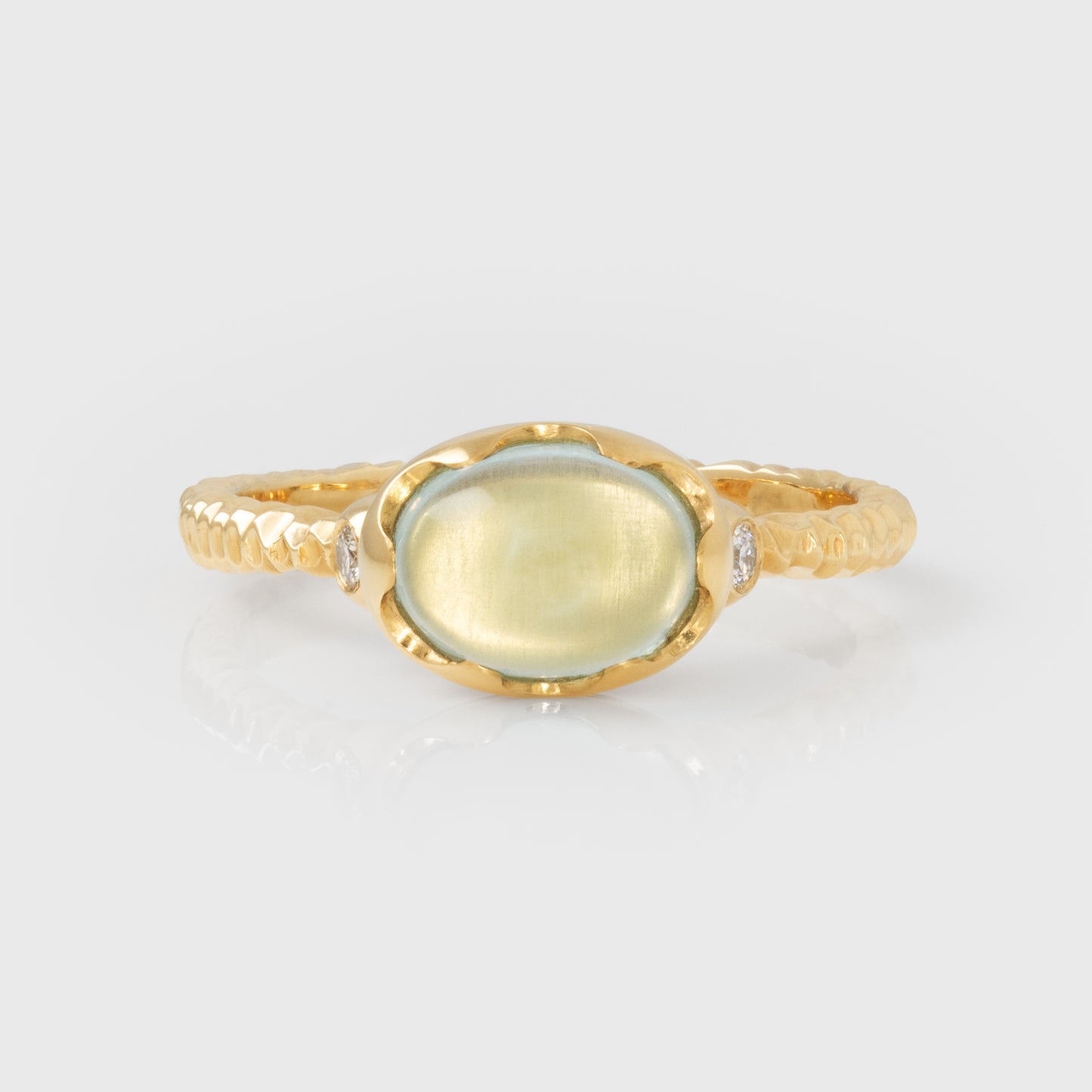 Gold ring with a green and blue gemstone on a light gray background