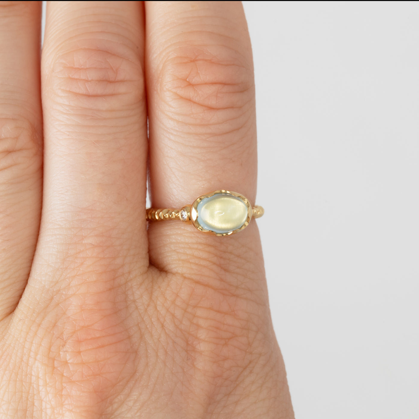 Gold ring with a gemstone on a hand against a white background