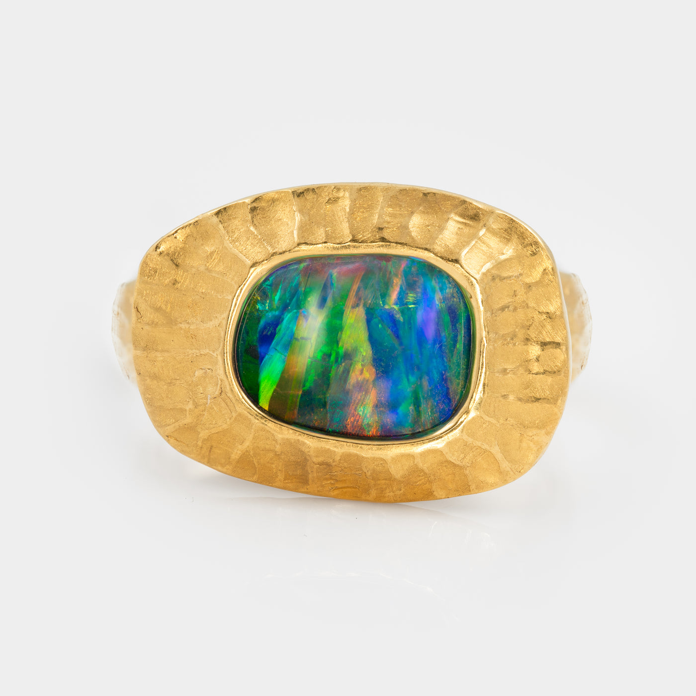 Blue, green, yellow, orange, and red boulder opal and gold ring on white background