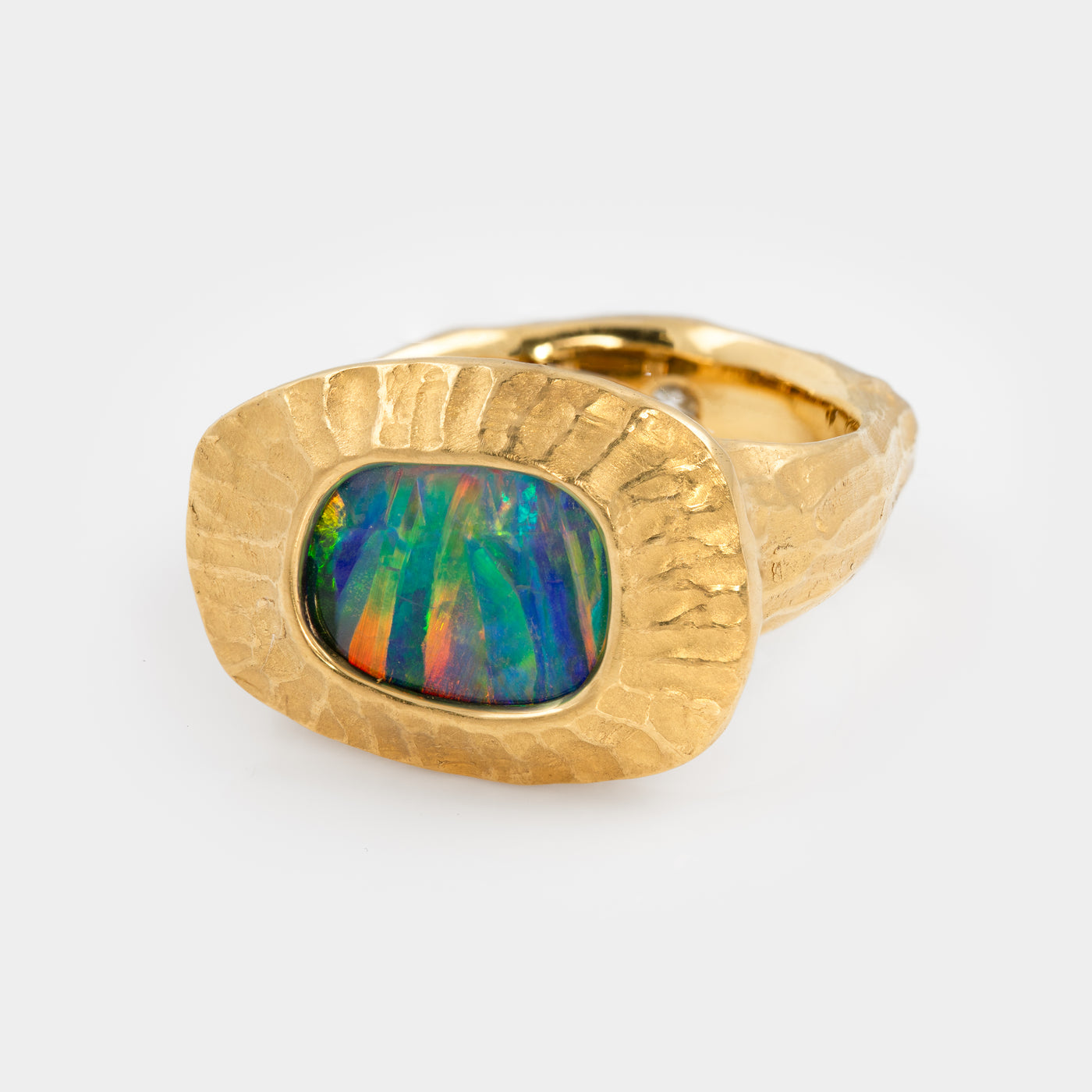Gold ring with a colorful boulder opal gemstone on a white background, three fourths view