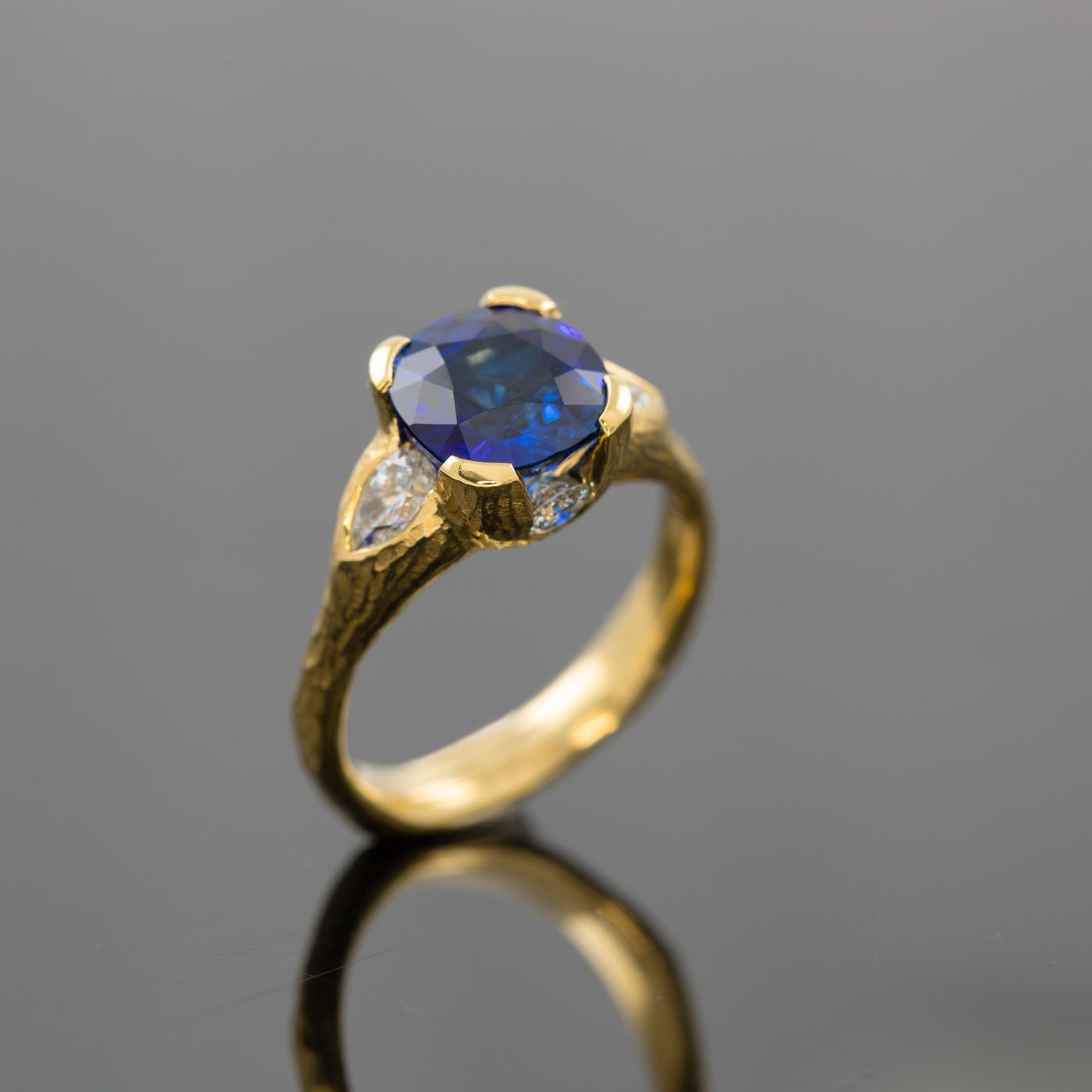 Gold ring with a blue gemstone on a gray background