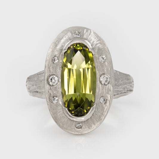 Platinum ring with a green gemstone on a white background