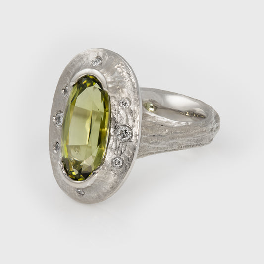 Platinum ring with a green gemstone on a white background