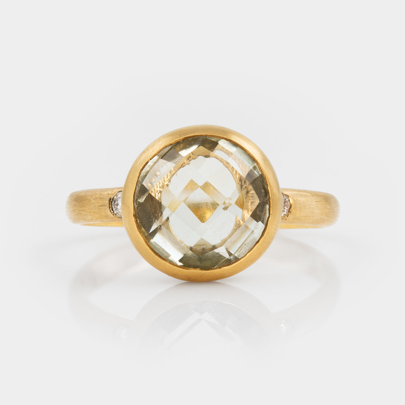 Gold ring with a large green amethyst gemstine on a white background
