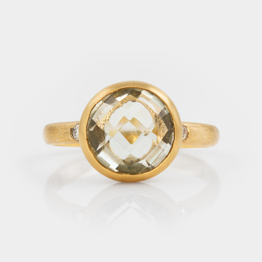 Gold ring with a large green amethyst gemstine on a white background