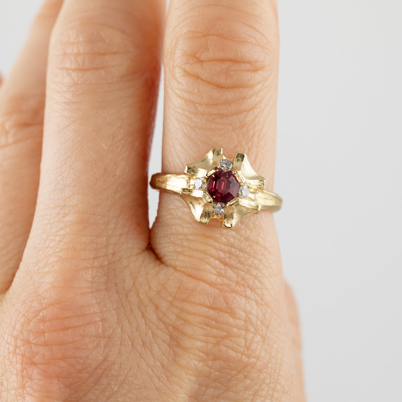Flower shaped gold ring with pink sapphire on hand