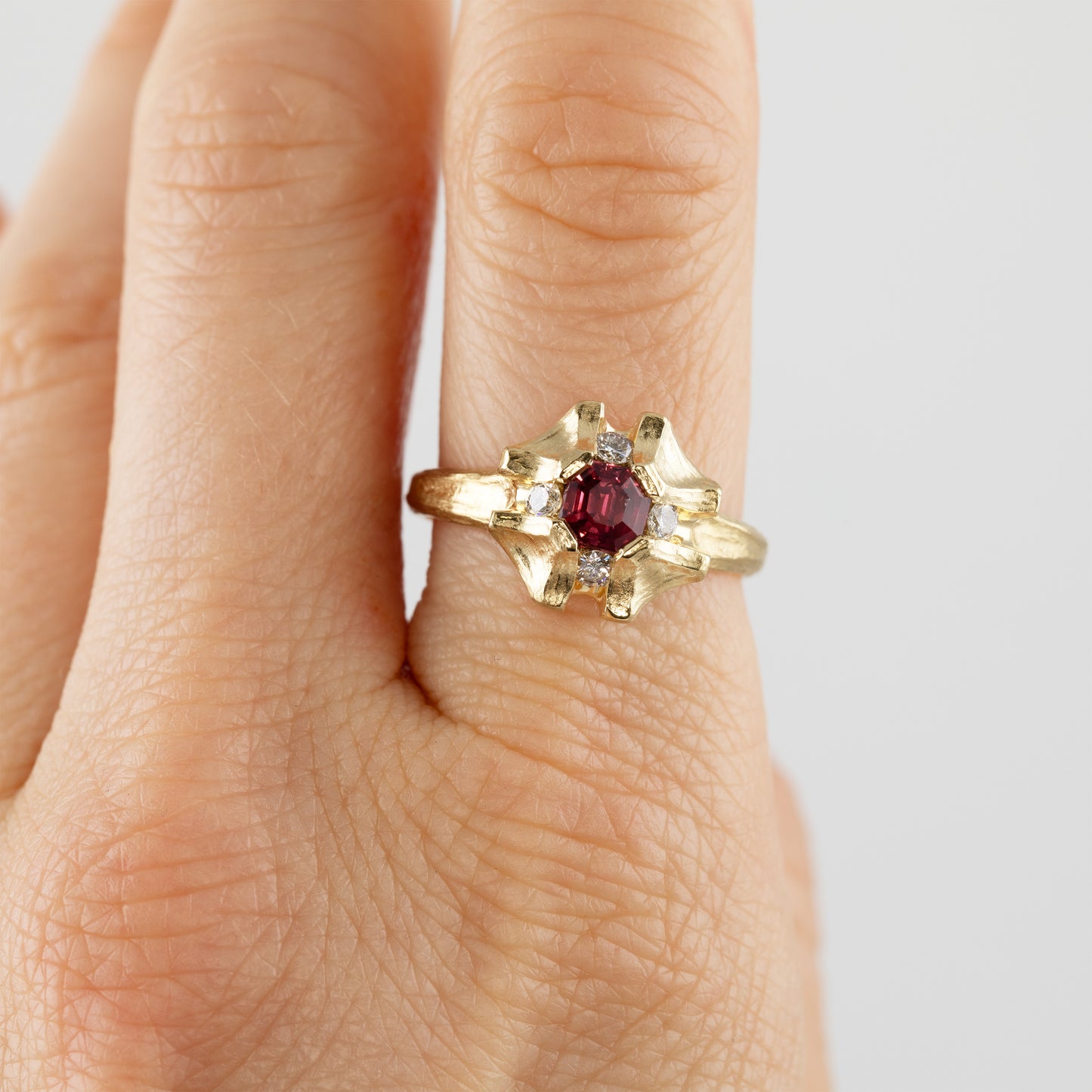 Flower shaped gold ring with pink sapphire on hand