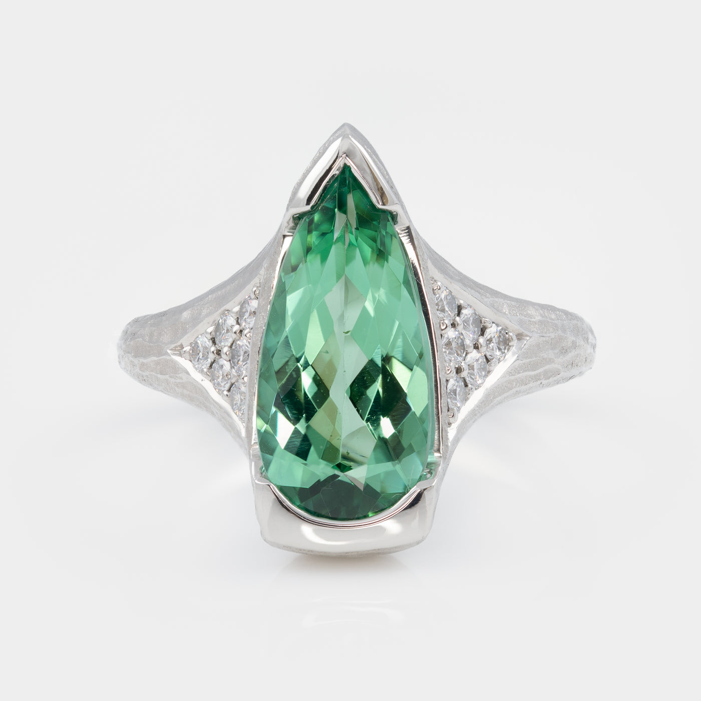Platinum ring with a green gemstone on a white background