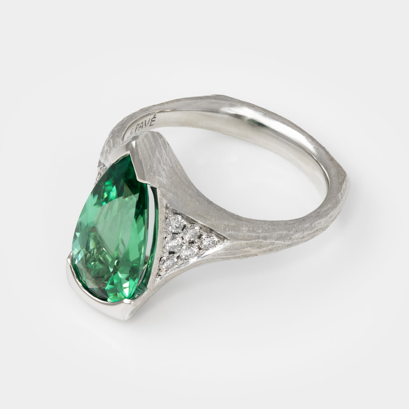 Platinum ring with a green gemstone on a white background