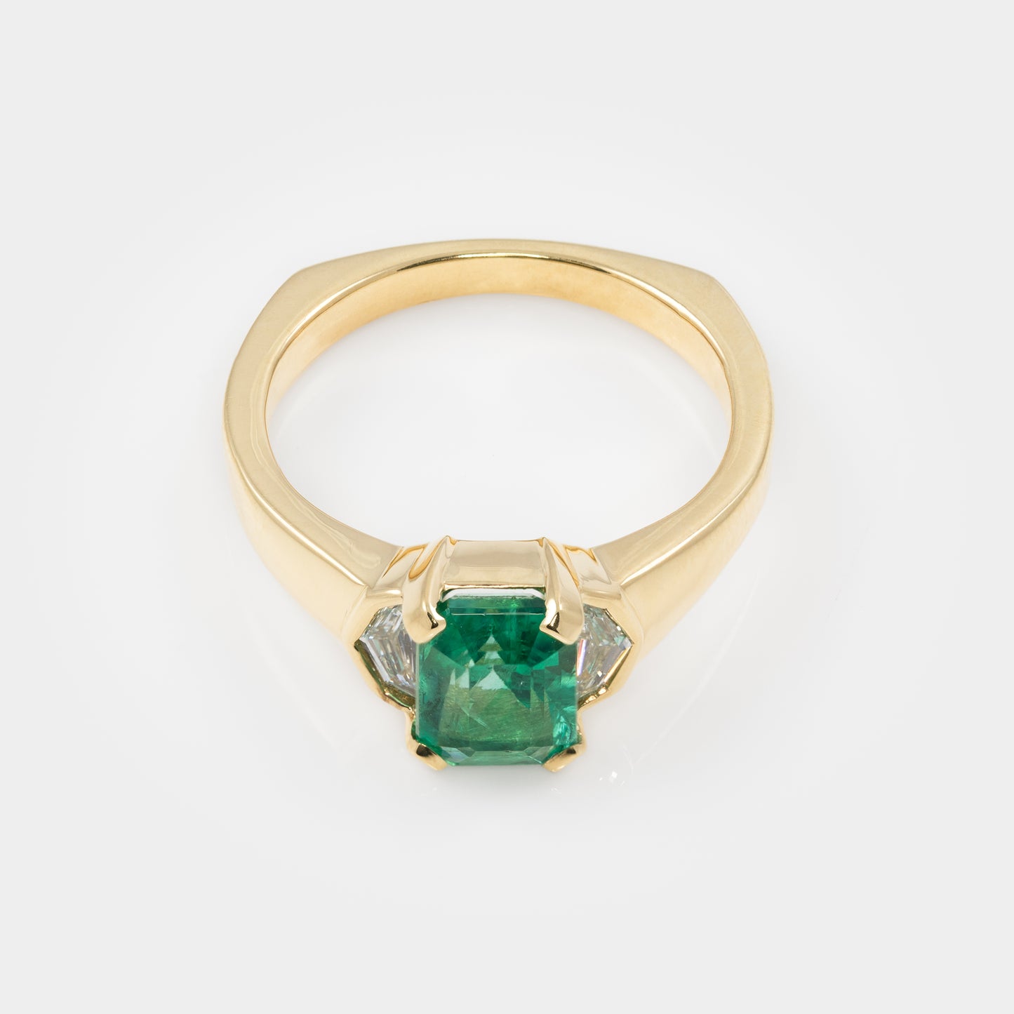 Gold ring with a green gemstone on a white background