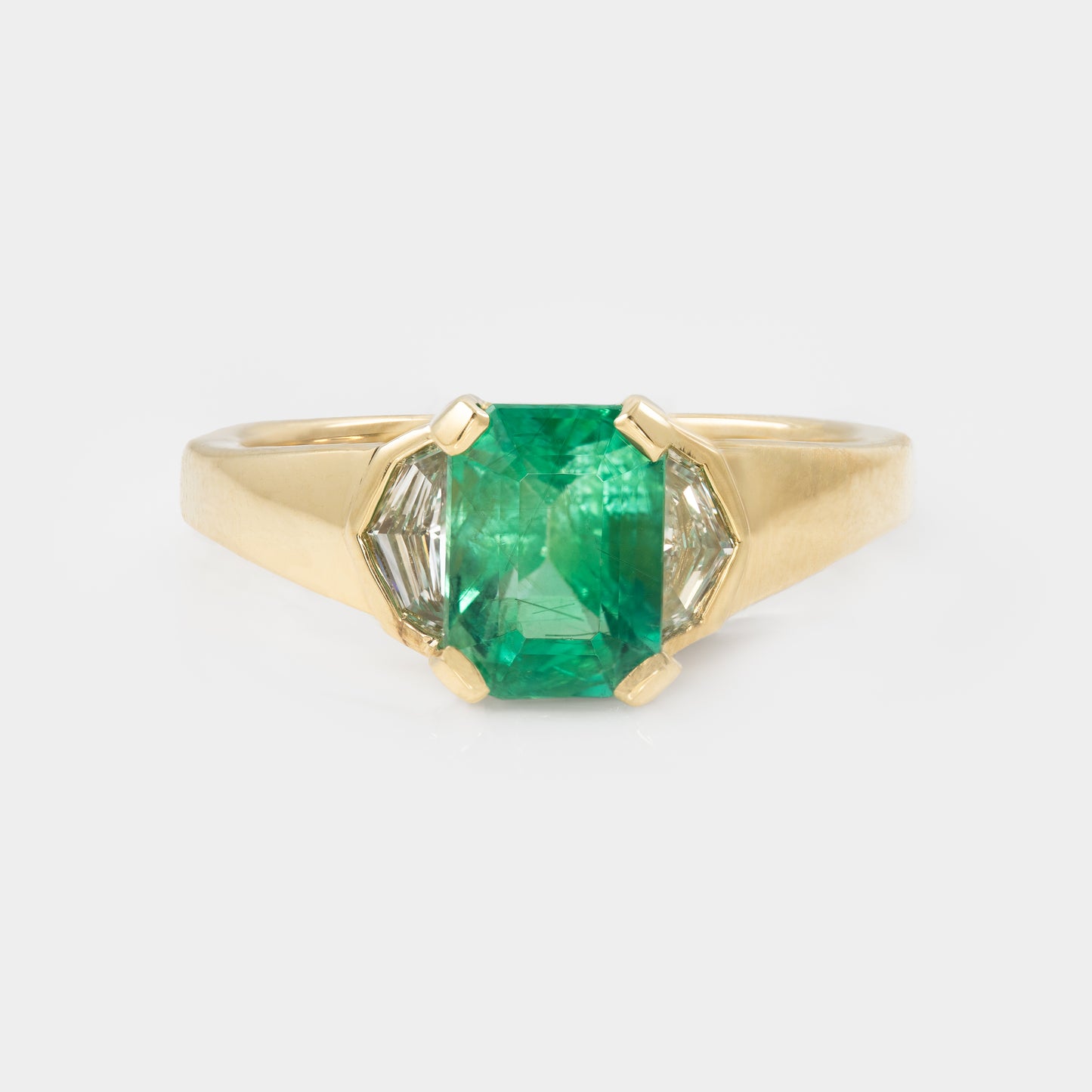 Gold ring with a green gemstone on a white background