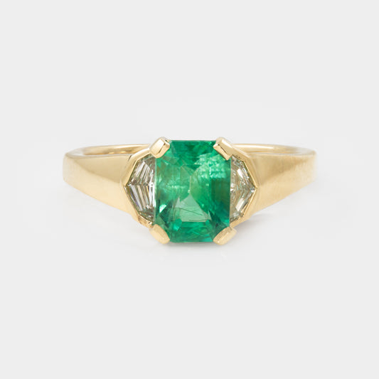 Gold ring with a green gemstone on a white background