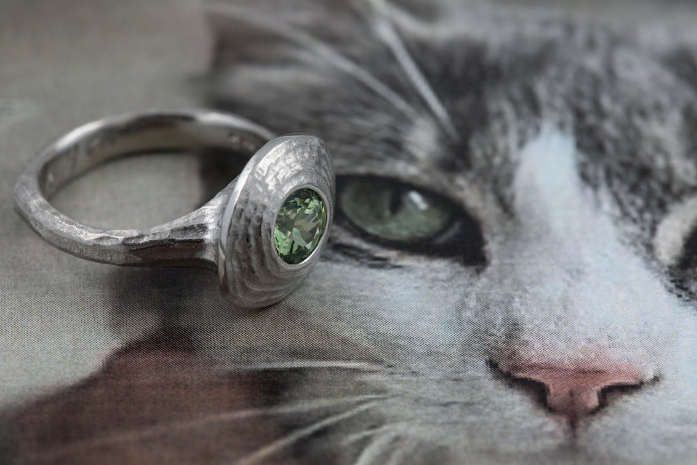 Platinum ring with a green gemstone on a cat's face