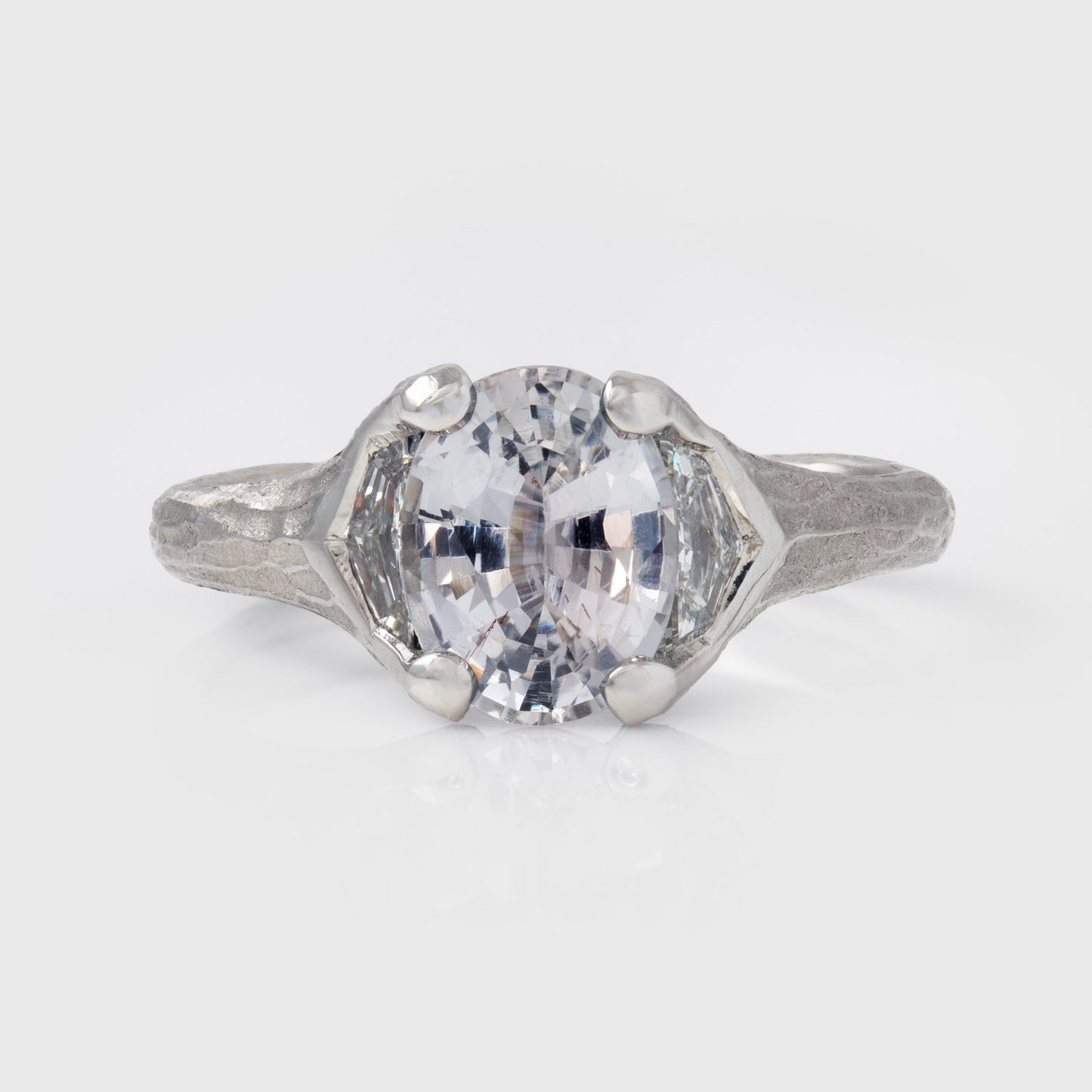 Platinum ring with a large gemstone on a light gray background