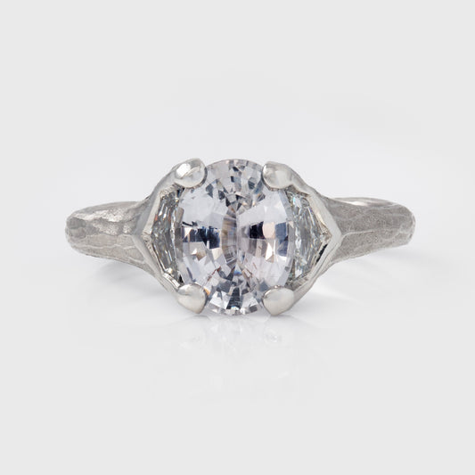 Platinum ring with a large gemstone on a light gray background