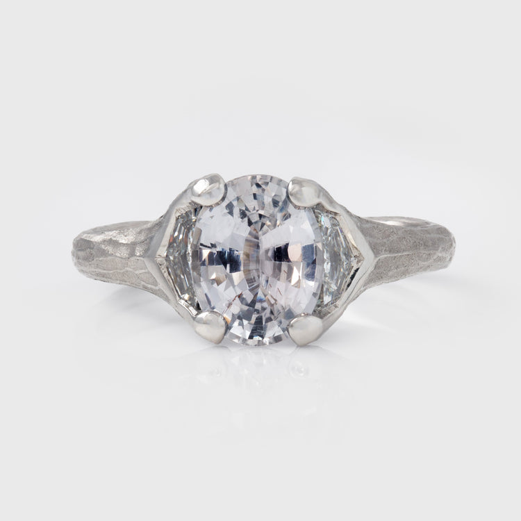 Platinum ring with a large gemstone on a light gray background
