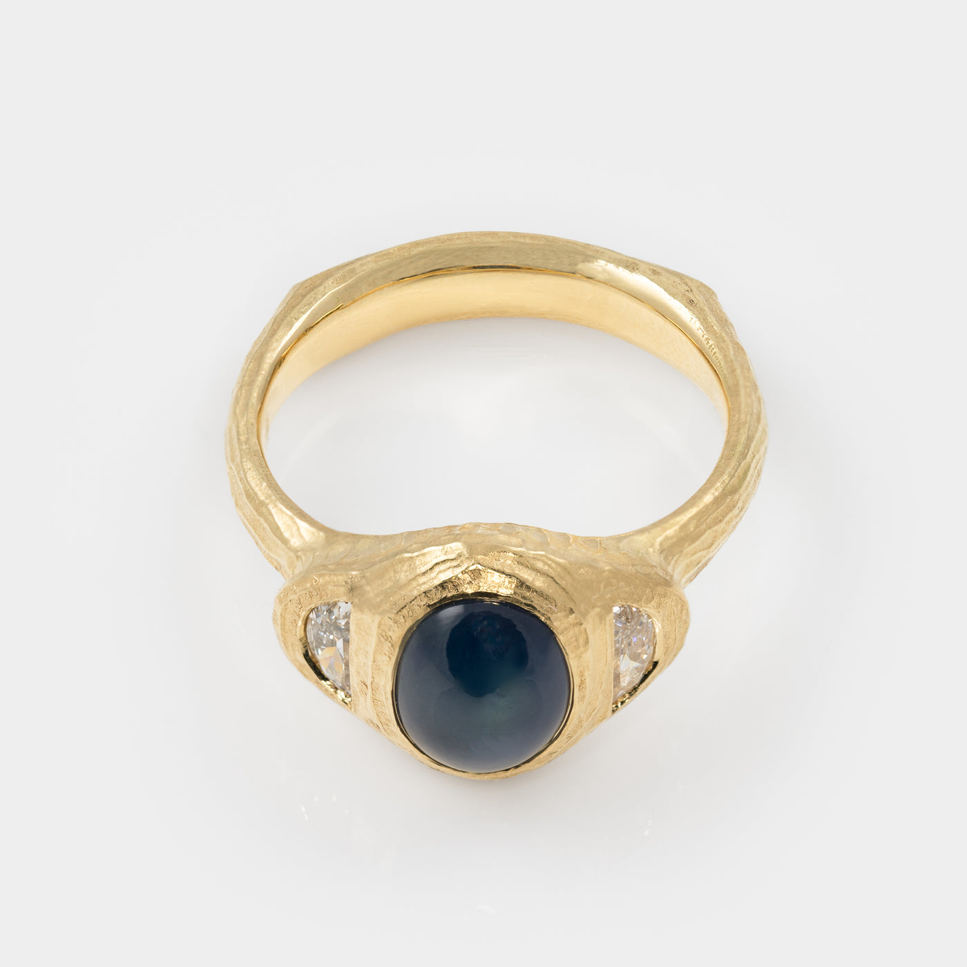Gold ring with blue star sapphire and side diamonds on white background top view