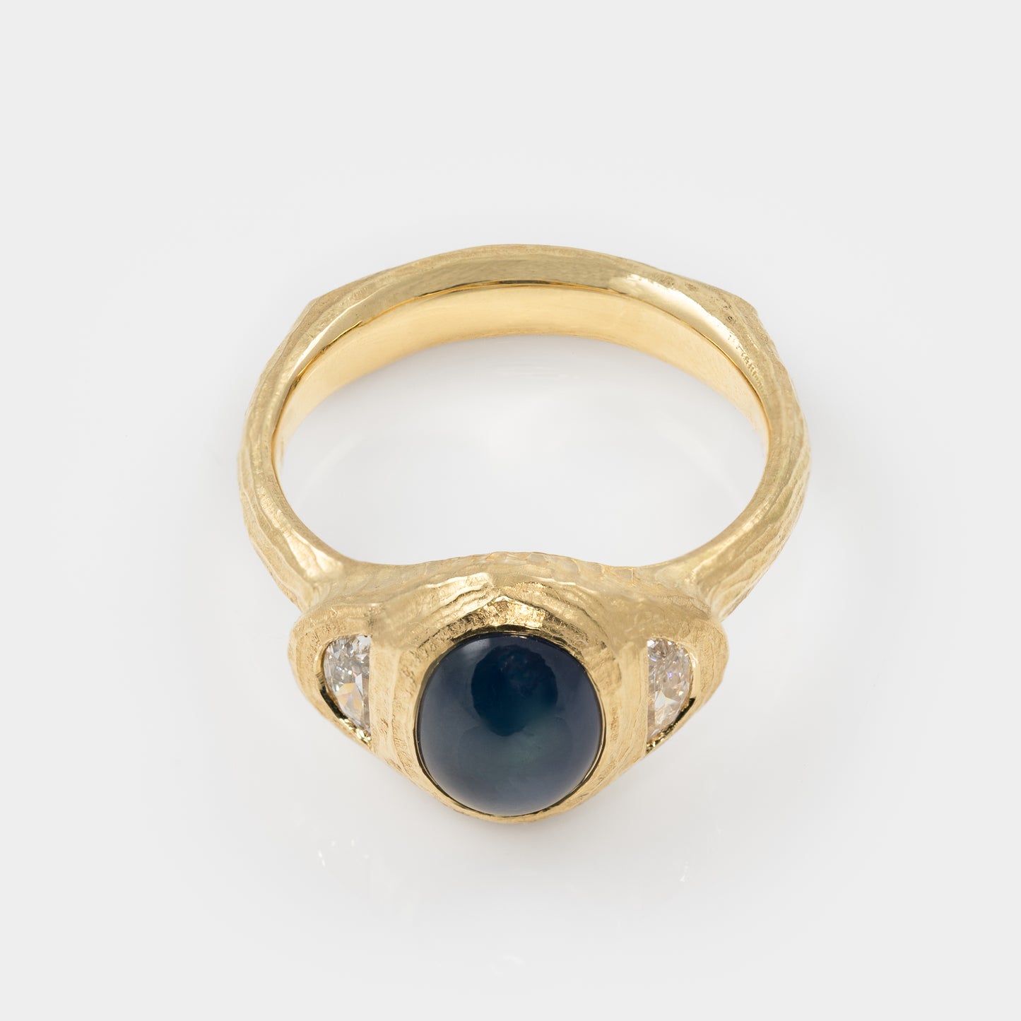 Gold ring with blue star sapphire and side diamonds on white background top view