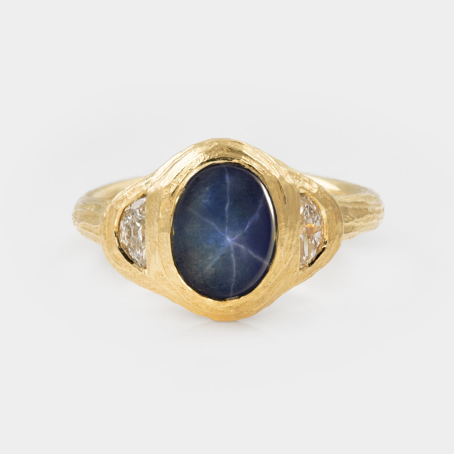 Gold ring with blue star sapphire and side diamonds on white background