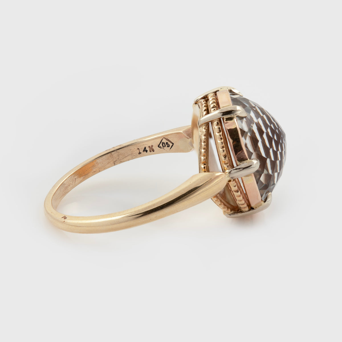 Side view of tri-color gold ring featuring a large champagne topaz center stone, side of band reads 14K [DS] photographed on a white background.