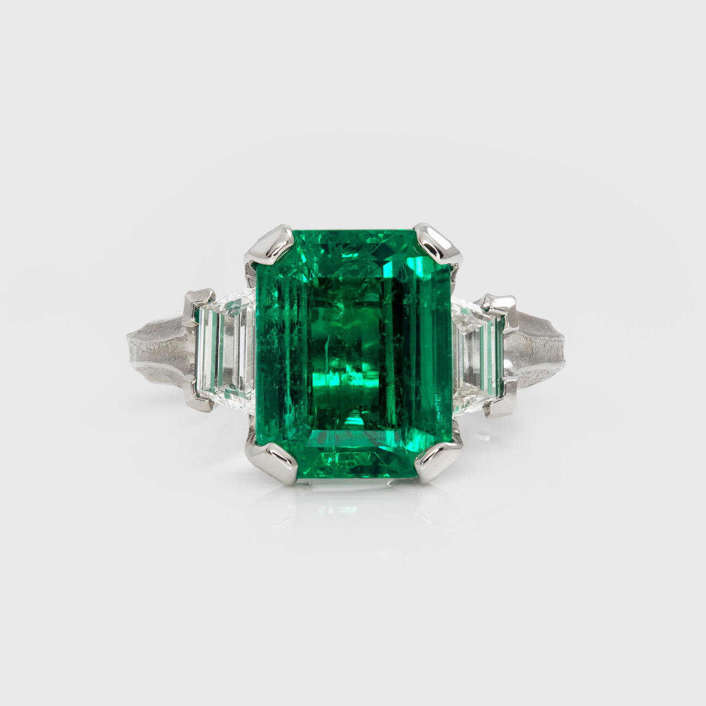 Emerald ring with diamond accents on a white background