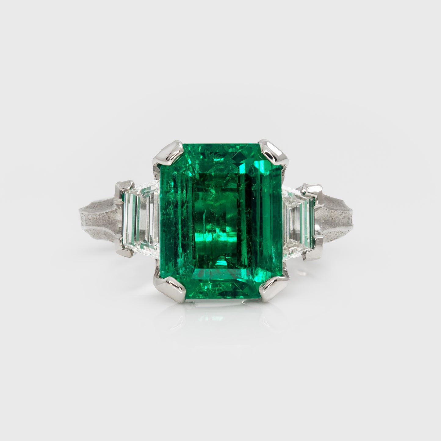 Emerald ring with diamond accents on a white background