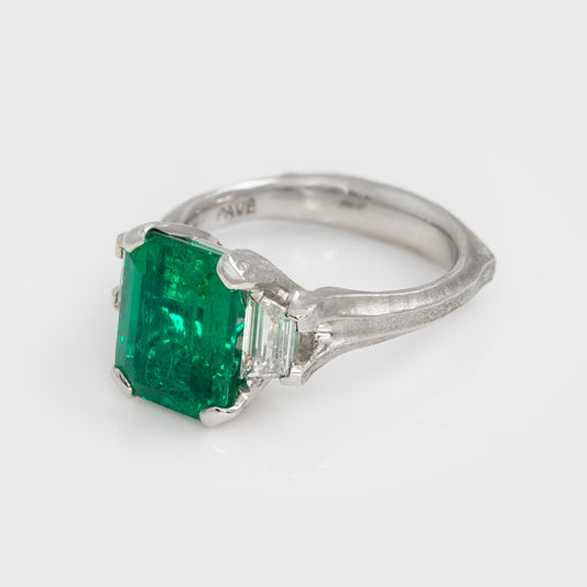 Platinum ring with a green gemstone on a white background