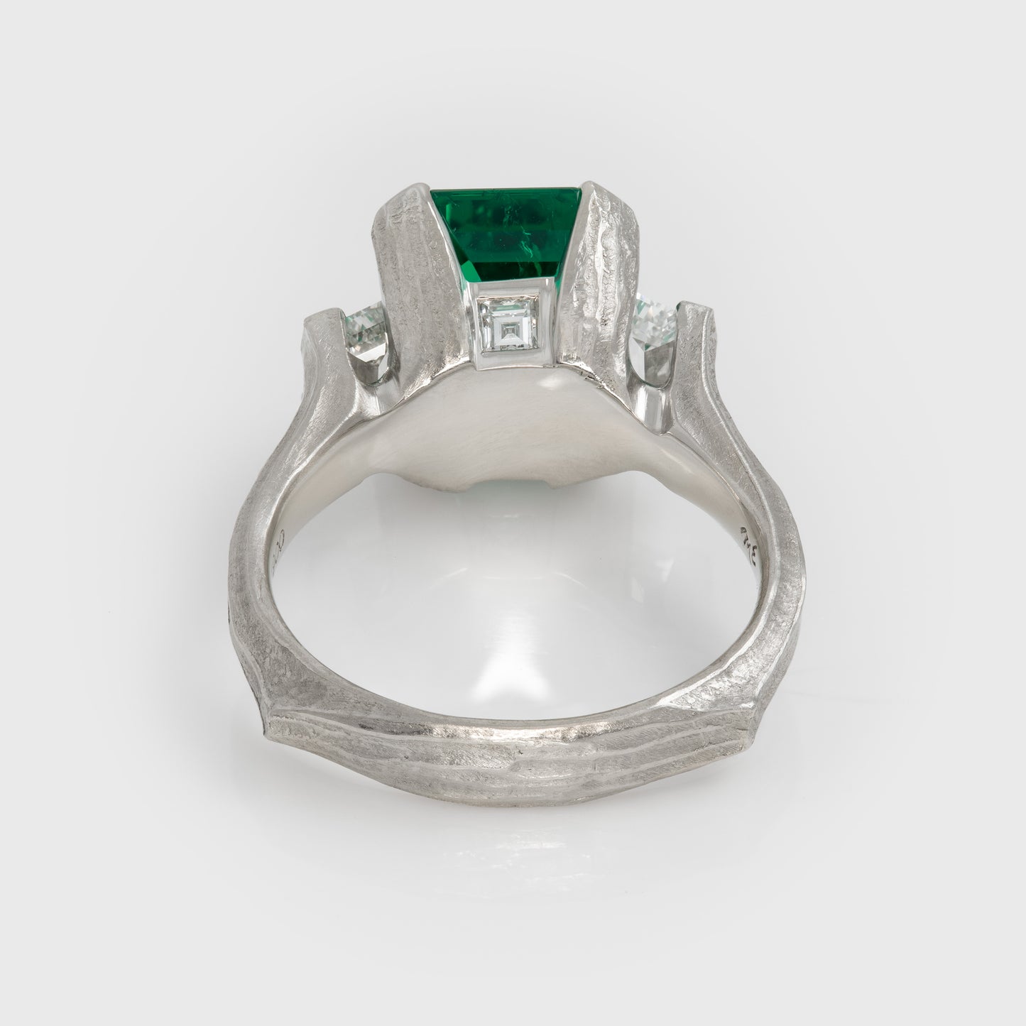 Platinum ring with a green gemstone on a white background
