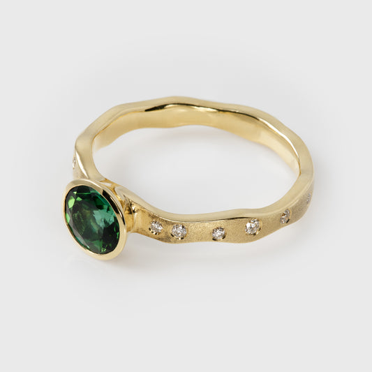 Gold ring with a green gemstone and small diamonds on a white background
