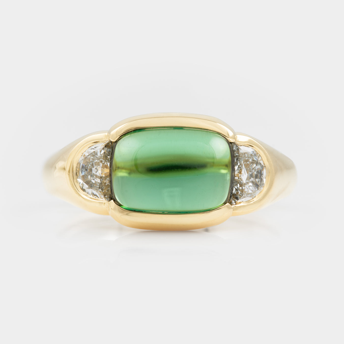Gold ring with a green gemstone and two smaller diamonds on a white background