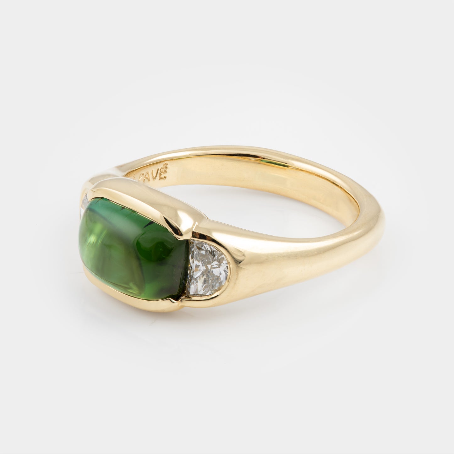 Gold ring with a green gemstone and diamond on a white background