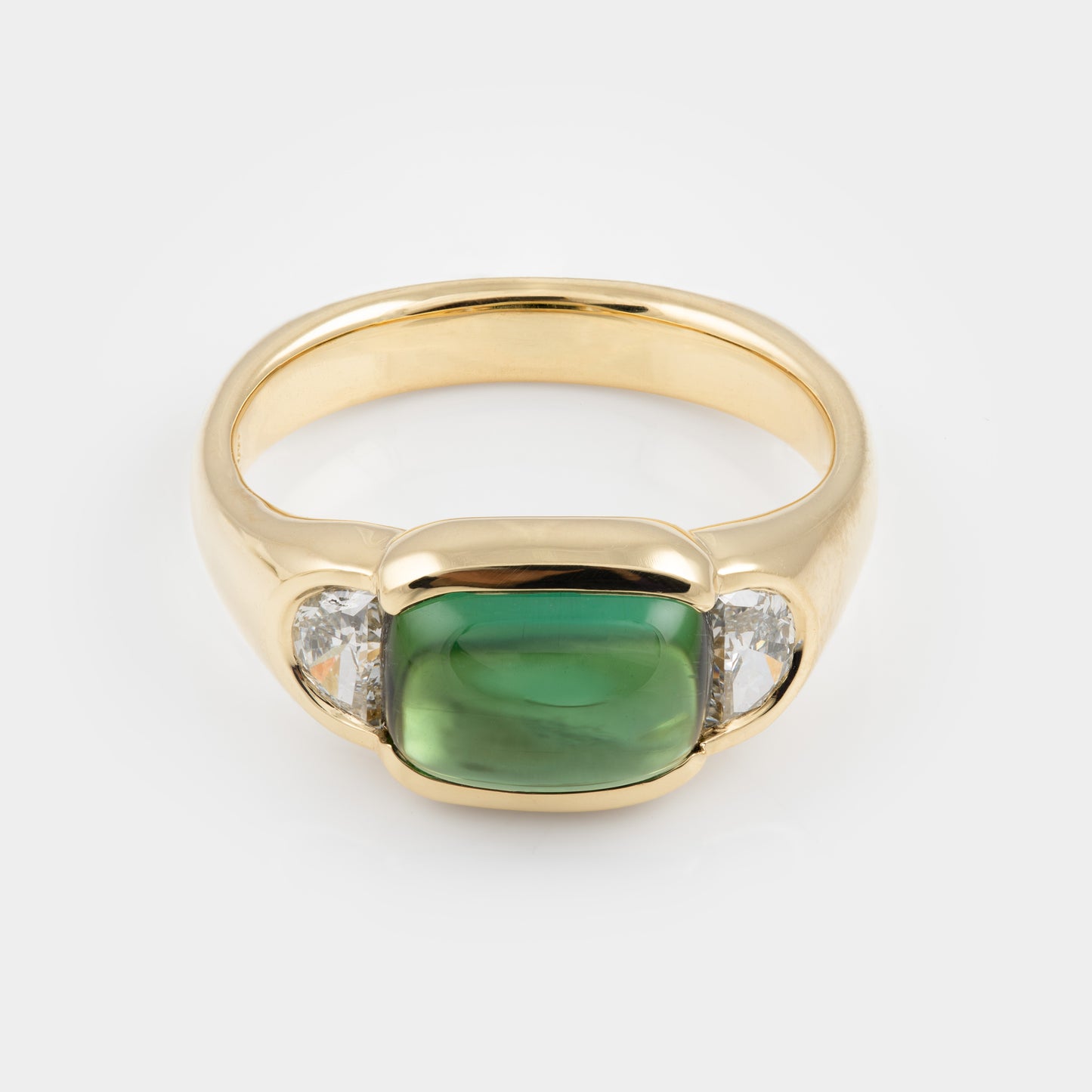 Gold ring with a green gemstone and diamonds on a white background