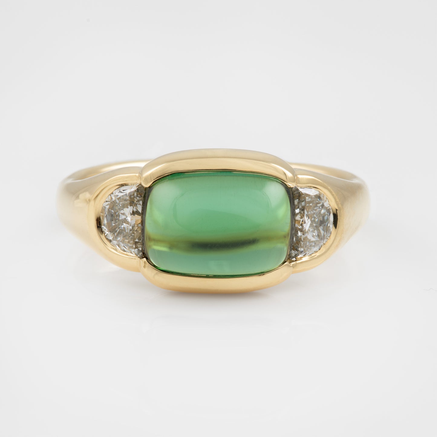 Gold ring with a green gemstone and two smaller diamonds on a white background