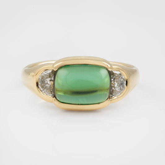 Gold ring with a green gemstone and two smaller diamonds on a white background