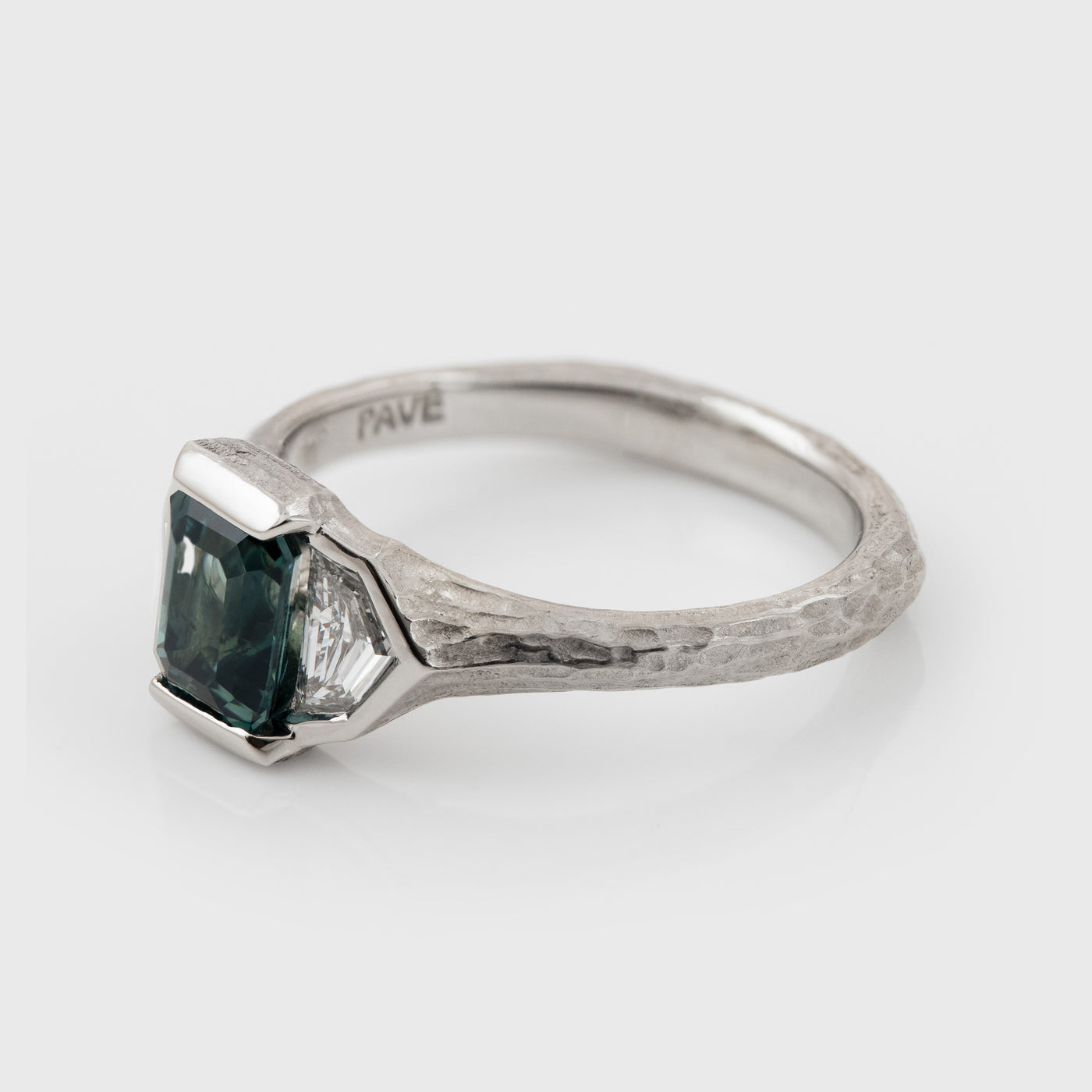 Platinum ring with green center gemstone and two accent diamonds on a white background