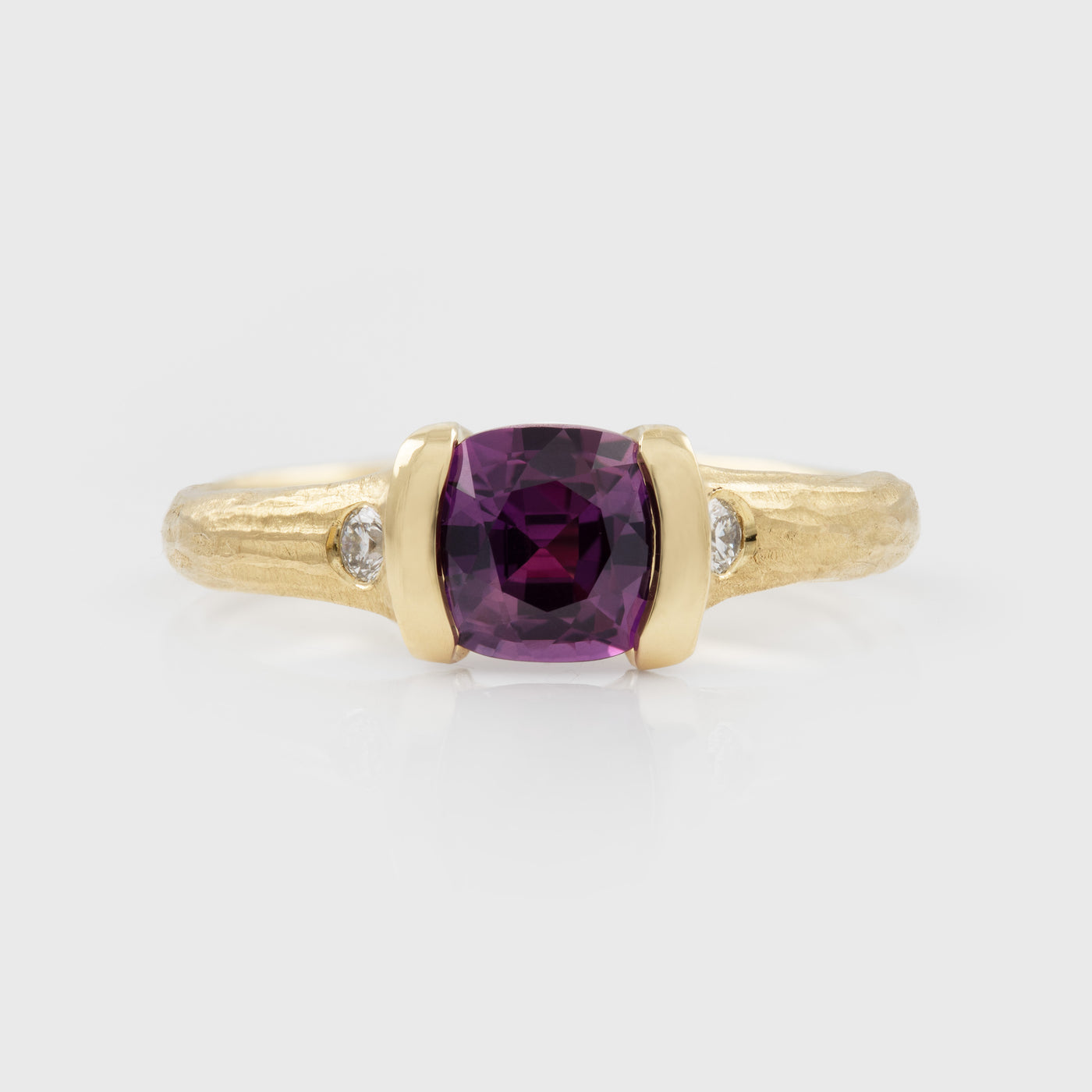 Gold ring with a purple gemstone and small diamonds on a white background